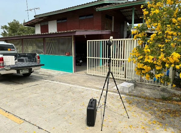 ไมโครโฟนตรวจวัดบนขาตั้งหน้าบ้านในชุมชน ระหว่างงานวัดเสียงของ GBS / A GBS noise survey microphone set up in front of a house